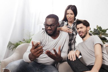 Üç arkadaş evde ve amazedly hareket eden telefon içinde birlikte izole vakit süre seyir sandalyelere oturan portresi