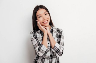 Ayakta ve mutlu bir şekilde fotoğraf makinesindeki Studio beyaz arka plan üzerinde seyir siyah saçlı güzel gülümseyen Bayan portresi