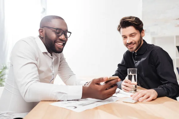 Retrato Dos Jóvenes Empresarios Multinacionales Alegres Sentados Mesa Hablando Felizmente — Foto de Stock