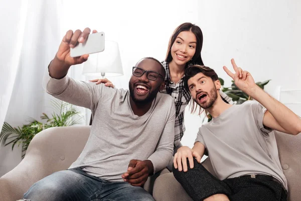 Retrato Tres Amigos Sonrientes Sentados Sillas Casa Tomando Fotos Divertidas —  Fotos de Stock