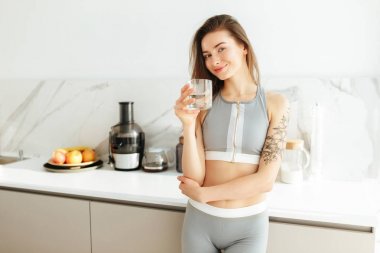 Mutfak sportif üst ayakta ve sevinçle kamera bardak su ile el arıyorum güzel Bayan portresi izole