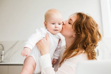 Ayakta ve izole onun şirin bebek öpüşme güzel annesinin portresi