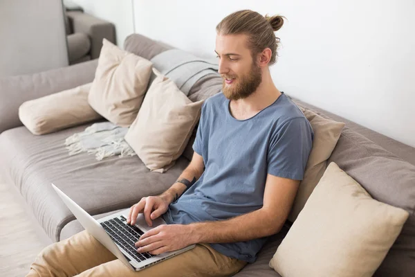 Retrato Hombre Joven Sentado Gran Sofá Gris Trabajando Ordenador Portátil — Foto de Stock