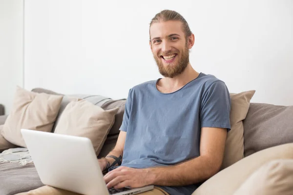 Retrato Joven Sonriente Sentado Gran Sofá Gris Con Portátil Mirando — Foto de Stock