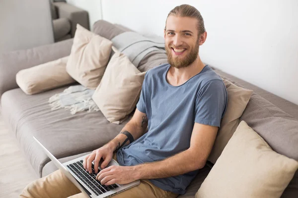 Retrato Joven Sonriente Sentado Gran Sofá Gris Con Portátil Mirando — Foto de Stock