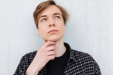 Ayakta ve sersem bir kenara beyaz arka plan üzerinde arayan genç adam portresi