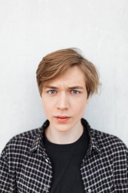 Ayakta ve amazedly fotoğraf makinesindeki beyaz arka plan üzerinde seyir genç adam portresi