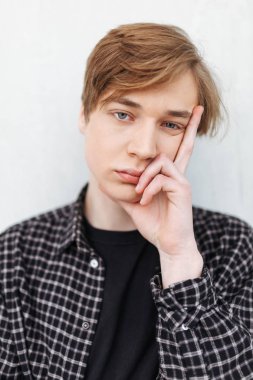 Ayakta ve yorgun fotoğraf makinesindeki beyaz arka plan üzerinde arayan genç adam portresi