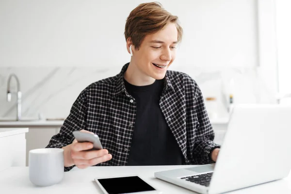 Retrato Jovem Fones Ouvido Sentado Com Celular Mão Olhando Alegremente — Fotografia de Stock