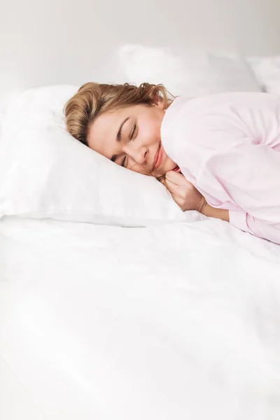 Portrait of beautiful smiling lady in pink pajamas sleeping in bed at home isolated