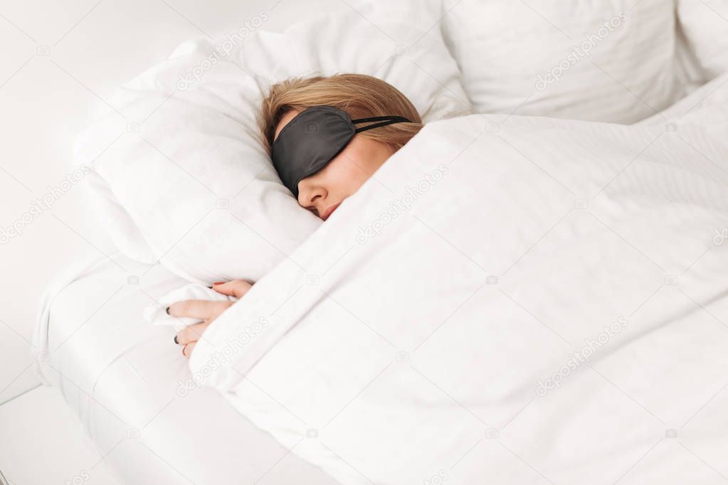 Portrait of lady wearing black eyes mask while sleeping in bed at home isolated