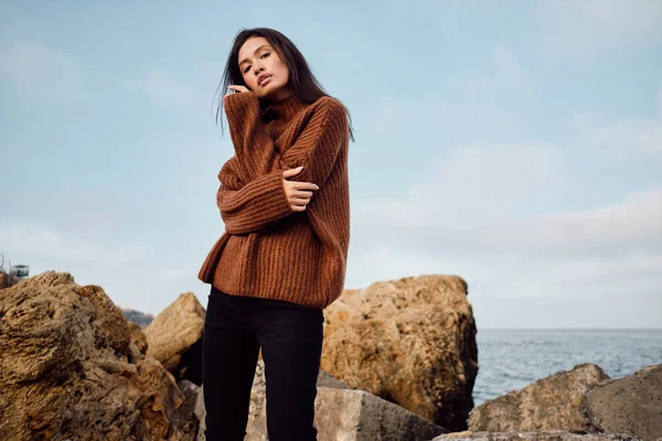 Attraktiv afslappet asiatisk pige i hyggelig strikket sweater sensuelt udgør ved havet - Stock-foto