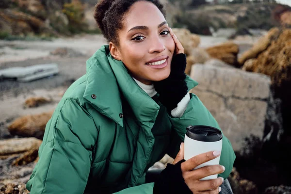 컵을 든 자켓을 입고 행복하게 야외 카메라를 보러 가는 평범 한 아프리카 계 미국인 소녀의 매력적 인 미소 — 스톡 사진