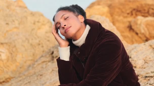 Hermosa Chica Afroamericana Tierna Chaqueta Plumón Posando Soñadoramente Sobre Piedras — Vídeo de stock