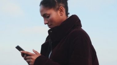 Açık havada cep telefonu kullanarak mutlu mesut gezen sıradan bir Afrikalı Amerikalı kızın fotoğrafını çekiyorum.