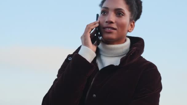 美しいですカジュアルアフリカ系アメリカ人の女の子でダウンジャケット上の携帯電話屋外 — ストック動画
