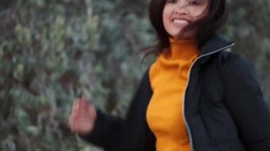 Çekici, sıradan bir Asyalı kız ceketli, koşuyor ve dışarıda kameraya bakıyor.