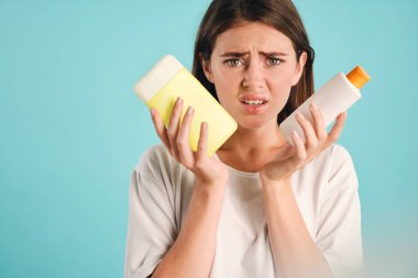 Plastik atık tutan genç üzgün kadın renkli arka planda kameraya bakıyor.