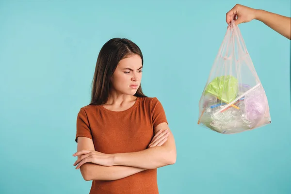 Sfrustrowana dziewczyna ze skrzyżowanymi rękami gniewnie patrząc na eko-torbę z plastikowymi odpadami na kolorowym tle — Zdjęcie stockowe