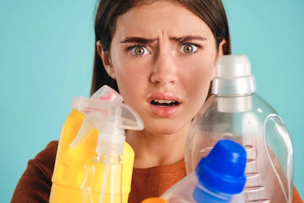 De cerca chica conmocionada con detergentes de plástico vacíos asustado mirando en la cámara sobre el fondo colorido —  Fotos de Stock