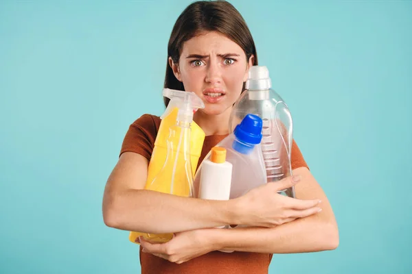 Zszokowana dziewczyna trzyma puste plastikowe detergenty w rękach przerażony patrząc w aparacie na kolorowe tło — Zdjęcie stockowe
