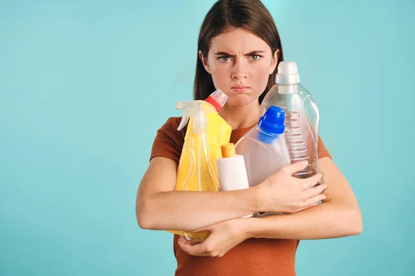 Podrażniona dziewczyna trzyma puste plastikowe detergenty w rękach wściekle patrząc w aparacie na kolorowe tło — Zdjęcie stockowe