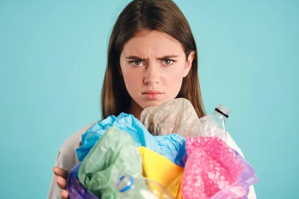 Portret zdenerwowanej dziewczyny trzymającej plastikowe odpady smutno patrząc w aparacie na kolorowe tło — Zdjęcie stockowe
