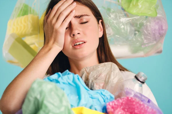 Zamknij się zmęczony zdenerwowany dziewczyna z tworzyw sztucznych odpadów wokół na kolorowe tło — Zdjęcie stockowe