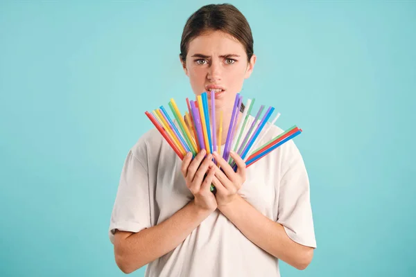 Confused girl holding colorful plastic straws in hands disappointedly looking in camera over colorful background. Stop using plastic straws — Stock Photo, Image