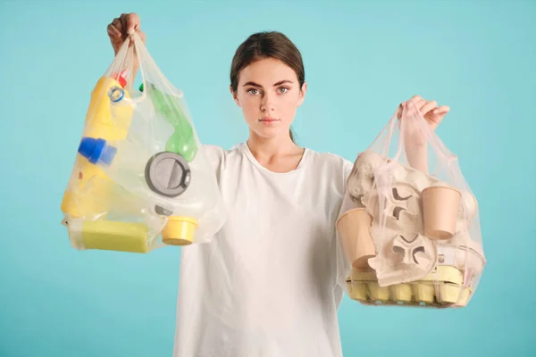 Aantrekkelijk meisje het houden van pakketten met het sorteren van plastic en dozen vuilnis zelfverzekerd kijken in de camera over kleurrijke achtergrond — Stockfoto