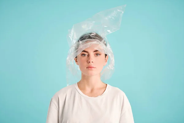 Zelfverzekerd meisje met plastic zak op hoofd aandachtig op zoek in de camera over kleurrijke achtergrond — Stockfoto