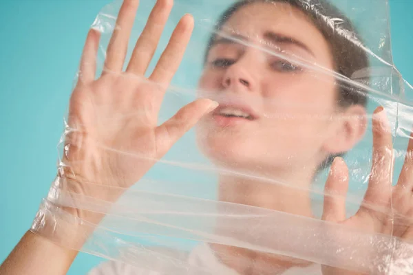 Θλιβερό κορίτσι πνίγεται σε πλαστική σακούλα δυστυχώς κοιτάζοντας στην κάμερα πάνω από πολύχρωμο φόντο — Φωτογραφία Αρχείου