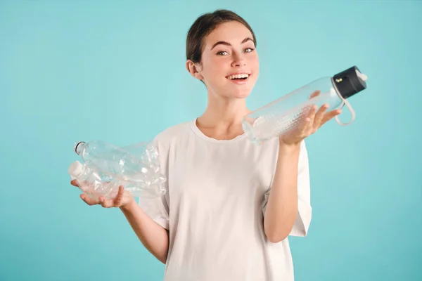 Attractive cheerful girl happily looking in camera choosing eco instead of plastic bottles over colorful background Royalty Free Stock Photos