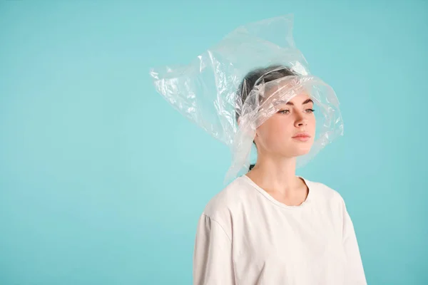 Side view of upset girl with plastic bag on head intently looking away over colorful background Stock Picture