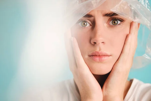 Close up sad girl with plastic bag on head scared looking in camera over colorful background Royalty Free Stock Photos