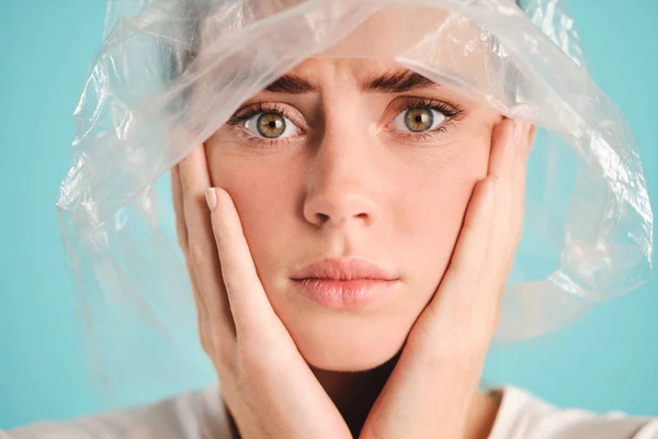 Close up sad girl with plastic bag on head anxiously looking in camera over colorful background Stock Photo