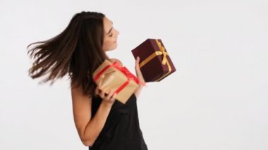 Güzel kahverengi saçlı kız elinde hediye kutuları beyaz arka planda neşe içinde dans ediyor.