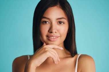 Güzel gülümseyen Asyalı esmer kız. Renkli arka planda kameraya bakıyor.