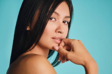 Güzel Asyalı esmer kız renkli arka planda kameraya şehvetle bakıyor.