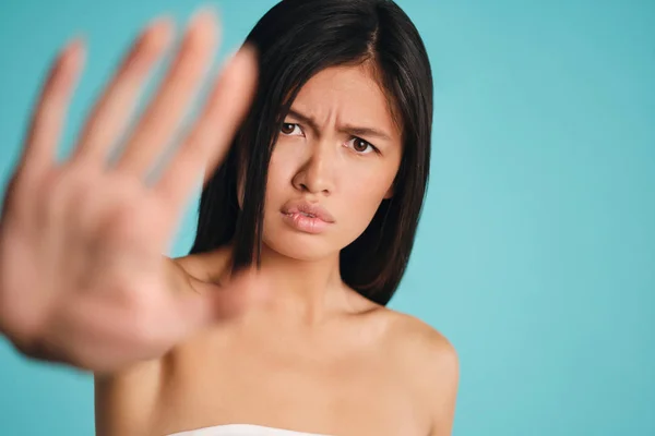 Menina morena asiática perturbada mostrando gesto de parada tristemente olhando na câmera sobre fundo colorido — Fotografia de Stock