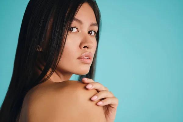 Close up beautiful Asian brunette girl intently looking in camera over colorful background — Stock Photo, Image