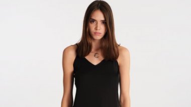 Young furious brown haired woman angrily looking in camera over white background