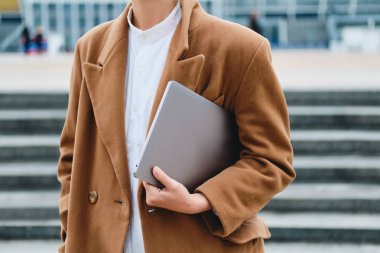 Şehir caddesinde dizüstü bilgisayarlı şık bir kadın.