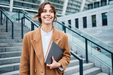 Laptoplu neşeli iş kadını mutlu bir şekilde dışarı bakıyor.