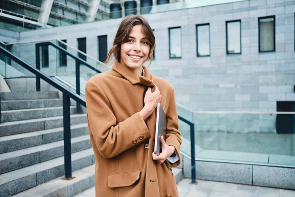 Giovane attraente donna d'affari elegante in cappotto con computer portatile sognante guardando lontano all'aperto — Foto Stock