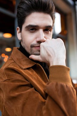 Genç, yakışıklı, sıradan bir adam, kameraya bakıyor ve caddedeki kafede dinleniyor.