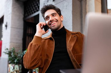 Genç, yakışıklı, sıradan bir adam cep telefonuyla konuşuyor. Cafe 'de laptopla çalışıyor.