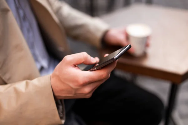 Cerca de hombre casual con café para ir usando el teléfono celular al aire libre — Foto de Stock