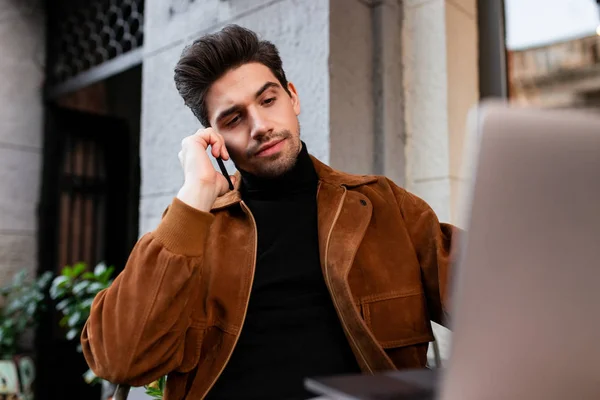 Junger gutaussehender, lässiger Mann, der selbstbewusst auf dem Laptop in einem Café auf der Straße arbeitet — Stockfoto