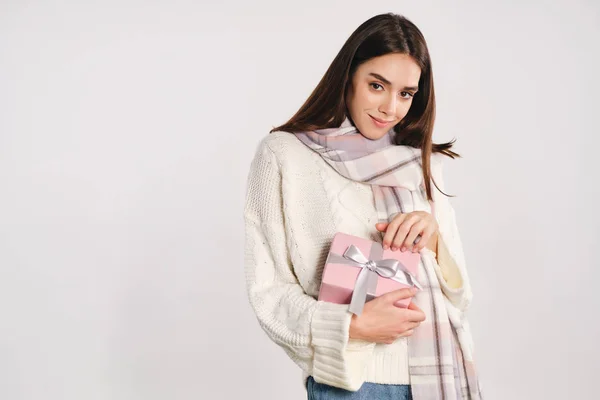 Piękna dziewczyna w przytulnym sweterku z szalikiem trzymając pudełko marzenie patrząc w aparacie na białym tle — Zdjęcie stockowe